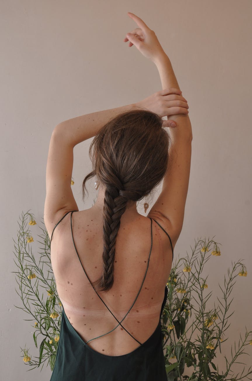 graceful woman with hand raised standing near plant